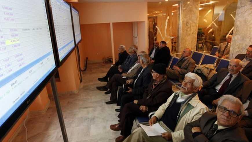 Investors monitor stock information on an electronic board at the Iraq Stock Exchange in Baghdad, January 7, 2013. REUTERS/Mohammed Ameen (IRAQ - Tags - Tags: BUSINESS)