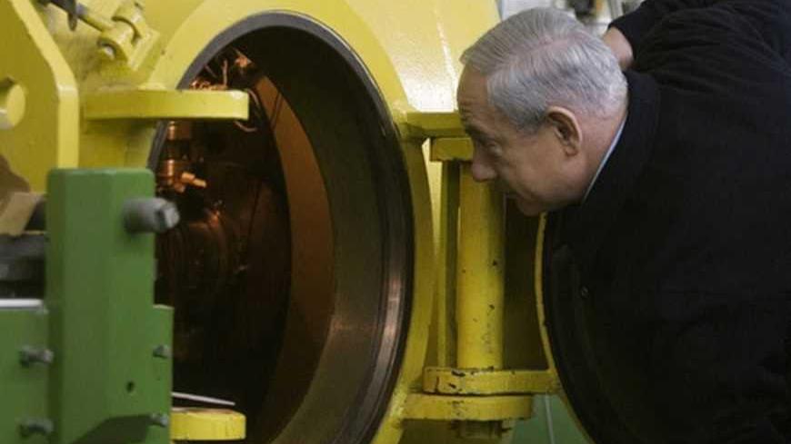 Israel's Prime Minister Benjamin Netanyahu looks inside a free-electron laser (FEL) during a visit at the Ariel University Centre in the West Bank Jewish settlement of Ariel January 8, 2013. Israel upgraded the Ariel campus to a university last month, a move that has put the school at the centre of a debate at the core of the Israeli-Palestinian conflict: how the settlements will figure in defining a future Palestinian state. REUTERS/Dan Balilty/Pool (WEST BANK - Tags: POLITICS EDUCATION)