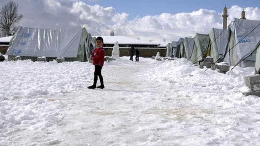 A Syrian child who is also a refugee, plays with snow outside tents in al-Marj, in the Bekaa valley January 10, 2013. REUTERS/Afif Diab (LEBANON - Tags: ENVIRONMENT SOCIETY)