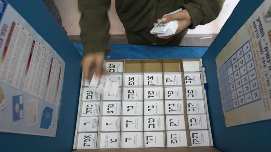 An Israeli soldier arranges ballots in a voting booth at a polling station in a military base in southern Israel January 21, 2013. Israeli soldiers started voting in Israel's parliamentary election on Sunday. Polling stations for the rest of Israel open on Tuesday. REUTERS/Ronen Zvulun (ISRAEL - Tags: POLITICS ELECTIONS MILITARY)