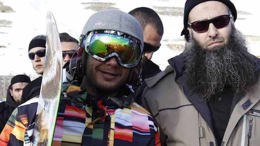 Sunni Muslim Salafist leader Ahmad al-Assir (R) poses with a snowboarder in Faraya ski area, in Mount Lebanon, January 24, 2013. Lebanese Army dispersed protesters and reopened a blocked road leading to Faraya in an attempt to  prevent al-Assir and his supporters from reaching the ski area, according to local media. REUTERS/Mohamed Azakir (LEBANON - Tags: POLITICS CIVIL UNREST SPORT RELIGION) - RTR3CW87