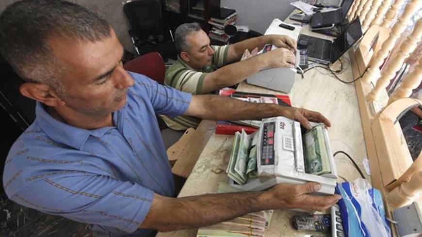 Men count wads of Iraqi dinars using money counting machines at a currency exchange shop in Baghdad October 1, 2012. Many Iraqis have lost faith in their dinar currency but to some foreign speculators, it promises big profits. The contrast underlines the uncertainties of investing in Iraq as the country recovers from years of war and economic sanctions. Picture taken October 1, 2012. To match IRAQ-ECONOMY/DINAR REUTERS/Saad Shalash (IRAQ - Tags: BUSINESS POLITICS)