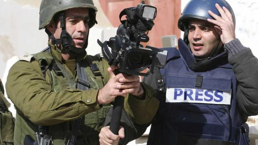 An Israeli army officer (C) grabs a camera from Reuters cameraman Yusri al-Jamal as he prevents him from covering news events in the West Bank city of Hebron January 2, 2009. REUTERS/Stringer (WEST BANK) - RTR2302T