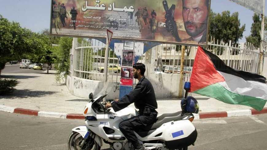 A Hamas policeman rides a motorcycle past a billboard promoting a film titled "Imad Aqel" in Gaza City August 3, 2009. "Imad Aqel", which had its premiere on Saturday, is the first feature film produced by the Islamist Hamas movement and the title is the name of a Palestinian militant whom Israel held accountable for the deaths of 13 soldiers and settlers. REUTERS/Ismail Zaydah (GAZA POLITICS SOCIETY ENTERTAINMENT) - RTR26DLS