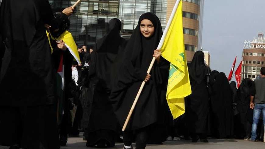A girl walks with the Hezbollah flag past Lebanon's Hezbollah supporters during a demonstration, organised by Lebanese and Palestinian factions, against Israel's military operation in Gaza, in front of the U.N. headquarters in Beirut November 17, 2012. Israeli aircraft bombed Hamas government buildings in Gaza on Saturday, including the prime minister's office, after Israel's cabinet authorised the mobilisation of up to 75,000 reservists, preparing for a possible ground invasion. REUTERS/Jamal Saidi (LEBANO