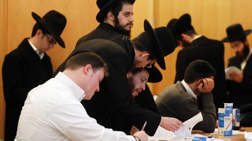 Ultra-Orthodox Jewish men sign documents at the offices of Israel's Administration for National Civil Service in Jerusalem January 6, 2013. For the first time since the August 1 expiration of the so-called Tal Law that exempted ultra-Orthodox seminary students from military conscription, dozens of scholars signed up on Sunday for alternative civilian service which, upon completion, will entitle them to avoid the draft. Some 1,300 seminary students are slated to join the program by August 2013, or until Isra