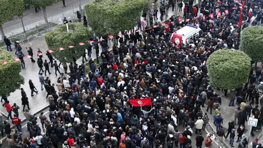 The body of Tunisian opposition Chokri Belaid (top R) arrives amidst tens of thousands of protesters as they demonstrate on Avenue Habib Bourguiba in Tunis February 6, 2013. Tunisia's secular opposition Popular Front said it was pulling out of the constituent assembly charged with writing a constitution after an opposition politician was killed on Wednesday. REUTERS/Anis Mili (TUNISIA - Tags: POLITICS CIVIL UNREST) - RTR3DF8E