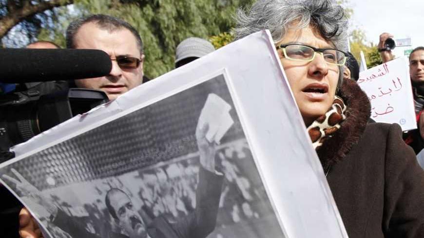 Basma Beliad, the widow of assassinated leftist politician Chokri Belaid, carries a poster of her husband as she's surrounded by journalists, during a demonstration calling for Prime Minister Hamadi Jebali and his cabinet to step down, next to the National Constituent Assembly in Tunis, February 11, 2013. A party led by interim President Moncef Marzouki said on Monday it had "frozen" its withdrawal from Tunisia's coalition government while talks continue on a political crisis sharpened by the killing of an 