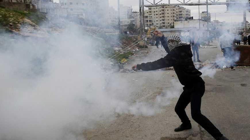 A Palestinian stone-thrower uses a sling to throw back a tear gas canister fired by Israeli troops during clashes outside Ofer prison near the West Bank city of Ramallah February 12, 2013. Clashes broke out on Tuesday between Palestinian stone-throwers and Israeli troops following a protest calling for the release of Palestinian prisoners from Israeli jails. REUTERS/Mohamad Torokman (WEST BANK - Tags: POLITICS CIVIL UNREST TPX IMAGES OF THE DAY) - RTR3DOU9