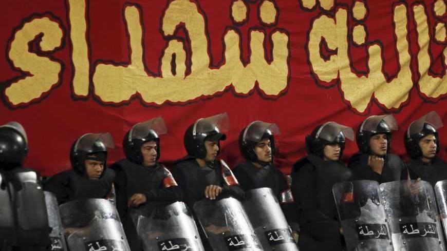 Riot police stand guard during a Confederation of African Football (CAF) Super Cup soccer match between Egypt's Al Ahly and Congo's AC Leopards at Borg El Arab Stadium, west of the Mediterranean city of Alexandria, 230 km (143 miles) north of Cairo February 23, 2013. The banner reads, "Martyrs' Place", in reference to the deaths of 74 Al Ahly fans in soccer violence between fans after a match against al-Masry in February last year. REUTERS/Amr Abdallah Dalsh (EGYPT - Tags: SPORT SOCCER CIVIL UNREST) - RTR3E