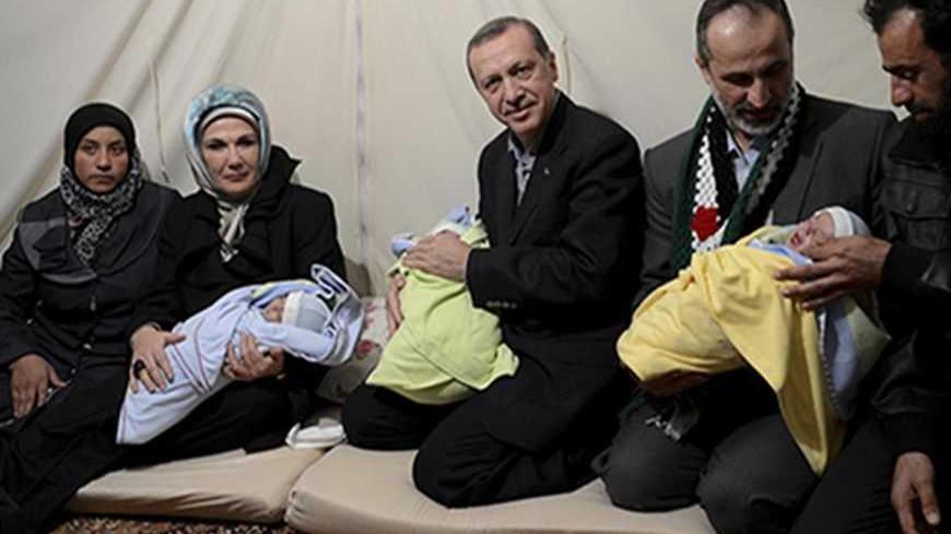 Turkish Prime Minister Tayyip Erdogan (C) and his wife Emine Erdogan (2nd L) pose with Syrian refugee triplet baby brothers whose names are Recep, Tayyip and Erdogan as they visit a refugee camp near Akcakale border crossing on the Turkish-Syrian border, southern Sanliurfa province, December 30, 2012, as they are flanked by the parents of the babies and head of the internationally-recognised, opposition Syrian National Council, Moaz al-Khatib (2nd R). REUTERS/Kayhan Ozer/Prime Minister's Press Office/Handou