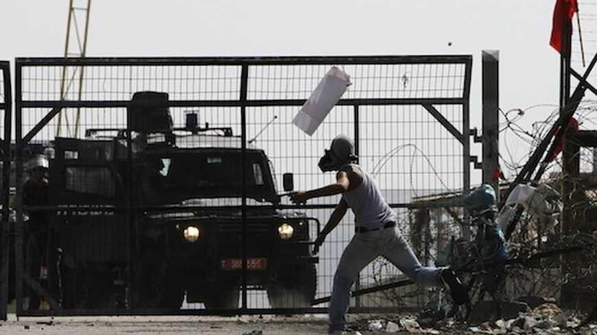 A Palestinian protester throws a stone towards Israeli security forces during clashes at a protest in solidarity with prisoners on hunger strike, outside Ofer prison near the West Bank city of Ramallah October 22, 2012. REUTERS/Mohamad Torokman (WEST BANK - Tags: POLITICS CIVIL UNREST) - RTR39FGM