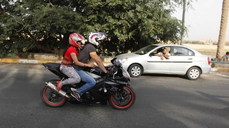 An Iraqi couple ride a motorbike during a biker show on Abu Nawas Street in Baghdad October 19, 2012.  Drag-racing in California, you say? No, this is Baghdad, where youthful rebellion and American biker style clash with  conservative mores in Iraq, a country where just a few years ago militias imposed their own radical Islamic views at gunpoint. Picture taken October 19, 2012. To match Feature IRAQ-CULTURE/BIKERS   REUTERS/Saad Shalash (IRAQ - Tags: SOCIETY SPORT MOTORSPORT) - RTR39IOY