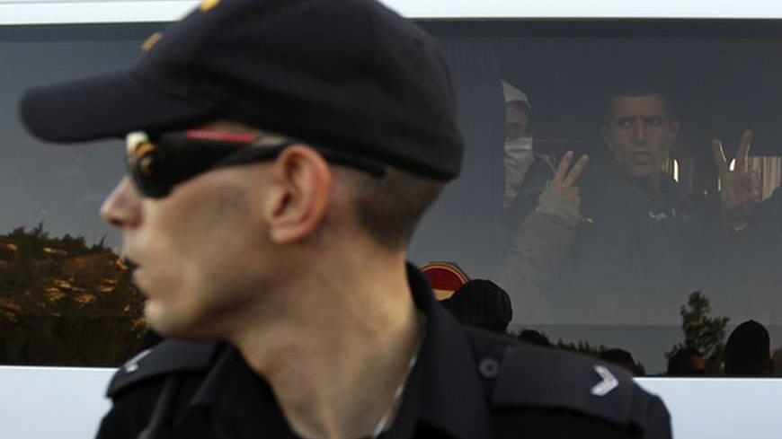 An Israeli police officer stands in front of Palestinian and foreign protesters gesturing from inside a vehicle after they were detained in an area known as "E1", which connects the two parts of the Israeli-occupied West Bank outside Arab suburbs of East Jerusalem January 15, 2013. Israeli police, using stun grenades, blocked about 50 Palestinian activists who tried on Tuesday to reoccupy tents they pitched last week on a patch of West Bank land which Israel wants for Jewish settlements. REUTERS/Ammar Awad 