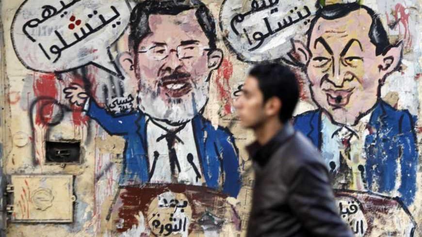 A protester walks past a graffiti during a march at Tahrir Square in Cairo, February 11, 2013. The march, was organized by Egyptians who oppose Egypt's President Mohamed Mursi and members of the ruling Muslim Brotherhood on the second anniversary of the resignation of veteran President Hosni Mubarak. The arabic words read, "After the revolution - let them speak" (L), "Before the revolution - let them play" (R). REUTERS/Amr Abdallah Dalsh  (EGYPT - Tags: POLITICS CIVIL UNREST) - RTR3DN7J