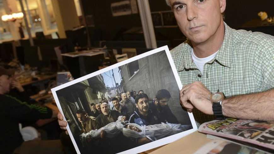 Paul Hansen of Sweden, a photographer working for the Swedish daily Dagens Nyheter, poses holding his picture that won the World Press Photo of the year for 2012, at Dagens Nyheter's office in Stockholm February 15, 2013. The photograph, which Hansen took on November 20, 2012, shows a group of men carrying the bodies of two dead children, who were killed in an Israeli missile strike on Gaza City, and won the top World Press Photo prize on Friday.        REUTERS/Fredrik Sandberg/Scanpix    (SWEDEN - Tags: ME