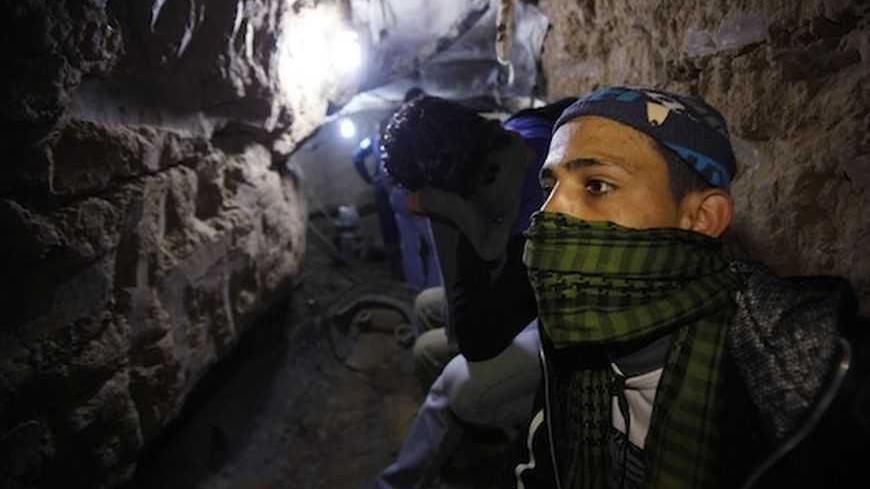 A Palestinian works inside a smuggling tunnel flooded by Egyptian forces, beneath the Egyptian-Gaza border in Rafah, in the southern Gaza Strip February 19, 2013. Egypt will not tolerate a two-way flow of smuggled arms with the Gaza Strip that is destabilising its Sinai peninsula, a senior aide to its Islamist president said, explaining why Egyptian forces flooded sub-border tunnels last week. To match Interview PALESTINIANS-TUNNELS/EGYPT REUTERS/Ibraheem Abu Mustafa (GAZA - Tags: POLITICS CIVIL UNREST) - R