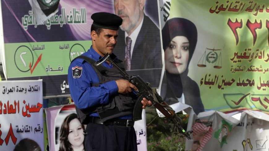 An Iraqi policeman stands guard next to election candidates posters in Baghdad March 3, 2010. Iraq will hold a parliamentary election on Sunday that could set it on a path to greater peace and prosperity or throw it back into the bloodshed and chaos that almost tore it apart in the seven years since the U.S. invasion. REUTERS/Ahmed Jadallah (IRAQ - Tags: POLITICS ELECTIONS) - RTR2B68L