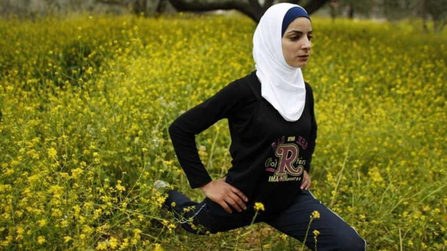 Palestinian runner Worood Maslaha, 20, stretches as she practises with her trainer Saher Jura (unseen) at a field belonging to her family in the West Bank village of Asira Ash-Shamaliya near Nablus March 27, 2012. Four Palestinians will participate in the London Olympics and joining Maslaha will be Gaza runner Bahaa al-Farra, Cairo-based swimmer Ahmed Jabreel and swimmer Sabeen Kharyoon from Bethlehem. Picture taken March 27, 2012. REUTERS/Ammar Awad (WEST BANK - Tags: SPORT OLYMPICS ATHLETICS) - RTR3001Q
