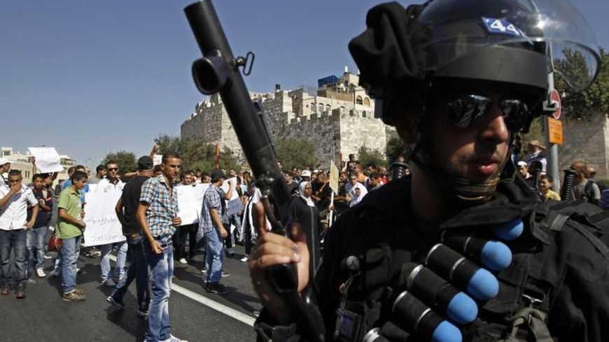 An Israeli policemen wearing a belt with rubber bullets stands near Palestinian protesters during clashes at a demonstration denouncing a U.S.-made film that mocks the Prophet Mohammed, near Damascus Gate outside Jerusalem's Old City September 14, 2012. Israeli police, some on horseback, used stun grenades and made a number of arrests outside Jerusalem's Old City as a few dozen demonstrators tried to march on to the nearby U.S. consulate. REUTERS/Ammar Awad (JERUSALEM - Tags: POLITICS CIVIL UNREST) - RTR37Y