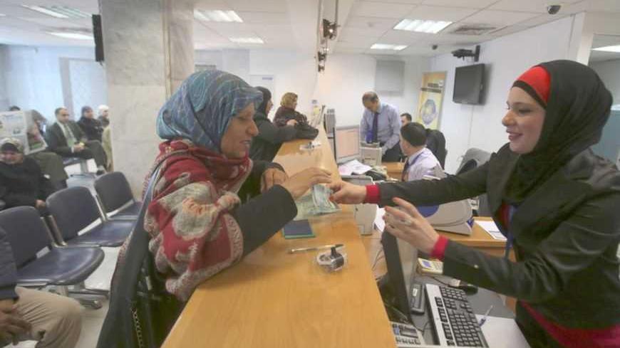 A Palestinian woman makes a withdrawal at the Housing Bank for Trade & Finance in the West Bank city of Ramallah January 22, 2013. A central bank in the making, the Palestine Monetary Authority (PMA) is a rare bright spot as the economy of the Palestinian territories struggles with Israeli sanctions. Enforcing on Palestinian banks a regimen of conservative lending that has kept bad loans minimal and guaranteed liquidity, the PMA's technocratic prowess is the pinnacle of a Palestinian drive to build institut