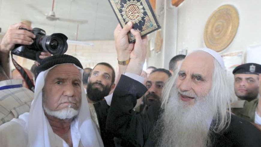 Rabbi and peace activist Menachem Froman (R) holds a Koran as it is given to Palestinians at a mosque after Monday's attack in the West Bank village of Beit Fajjar near Bethlehem October 5, 2010. Jewish settlers on Tuesday gave Korans to Palestinians in the West Bank village whose mosque was burned in an attack blamed on militants in the settler movement. REUTERS/Ammar Awad (WEST BANK - Tags: POLITICS CIVIL UNREST RELIGION) - RTXT2UB