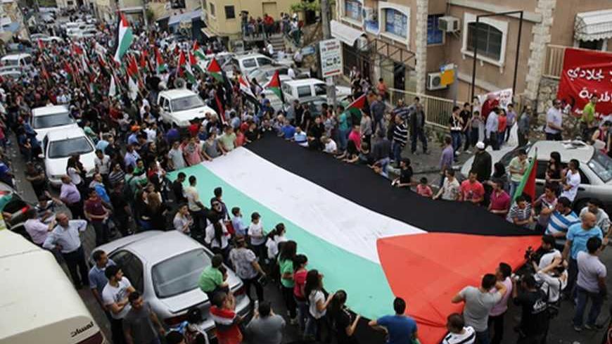 Israeli Arab demonstrators carry a huge Palestinian flag during a demonstration marking Land Day in the northern town of Sakhnin March 30, 2013. Land Day is the annual commemoration of protests in 1976 against Israel's appropriation of Arab-owned land in Galilee. REUTERS/Ammar Awad (ISRAEL - Tags: CIVIL UNREST ANNIVERSARY) - RTXY307