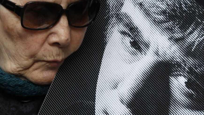 Turkish author and human rights activist Adalet Agaoglu leans over a poster of late Turkish-Armenian journalist Hrant Dink as she stands next to the spot, where Dink was killed, outside the Agos newspaper building during a commemoration to mark his fifth death anniversary in Istanbul January 19, 2012. A man was sentenced to life in prison in Turkey on Tuesday for the 2007 killing of prominent Turkish-Armenian journalist Hrant Dink in a verdict that drew criticism from rights groups for failing to explore al