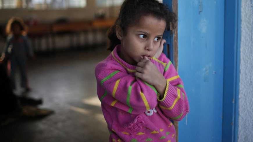 A displaced Palestinian girl, who fled her family's house, stands outside a classroom as she stays at a United Nations-run school in Gaza City November 20, 2012. From the sandy expanses of the northern Gaza Strip, Palestinian families are fleeing their homes destroyed by airstrikes, but refuse to blame the Hamas rocket crews who draw Israeli fire. REUTERS/Ahmed Jadallah  (GAZA - Tags: MILITARY POLITICS CONFLICT SOCIETY) - RTR3AN2J