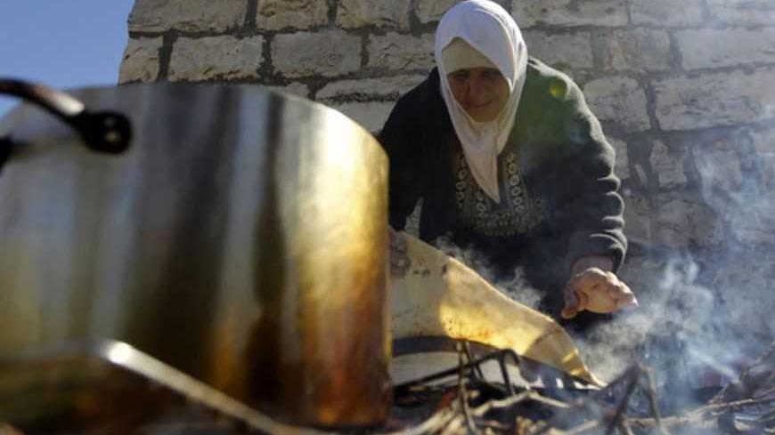 A woman prepares bread for Palestinian and foreign activists protesting against what they say is Israel's denial of access to their farmland, in the village of Khirbet Zakaria, near the settlement bloc of Gush Etzion, February 4, 2013. REUTERS/Ammar Awad (WEST BANK - Tags: POLITICS FOOD CIVIL UNREST) - RTR3DC5V