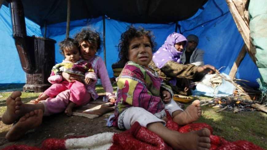 A Syrian refugee family sits in front of their makeshift tent in the town of Viransehir in Sanliurfa province, southeast Turkey, February 10, 2013. Some 50 families, mostly from villages near Syria's Aleppo, prefer to settle in the outskirts of Viransehir instead of refugee camps run by the Turkish government. According to the families, this allows them to work as seasonal agricultural workers.  REUTERS/Umit Bektas (TURKEY - Tags: POLITICS SOCIETY IMMIGRATION BUSINESS EMPLOYMENT CIVIL UNREST) - RTR3DL1D