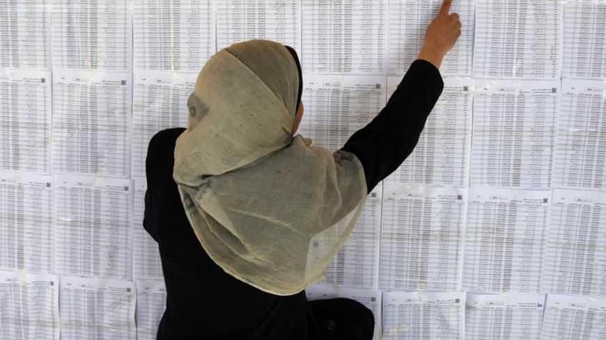 A Palestinian woman looks for her name on voter lists put up on a wall inside a school in Gaza City February 11, 2013. The Palestinian Central Election Commission (CEC) began on Monday registering voters in Gaza and the West Bank for an upcoming election that is hoped to help with healing nearly six years of political rifts among rival factions.  REUTERS/Ibraheem Abu Mustafa (GAZA) - RTR3DMRA