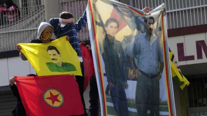 Turkish-Kurdish demonstrators hold a poster, which shows jailed Kurdistan Workers' Party (PKK) leader Abdullah Ocalan (R) with late Kurdish activist Sakine Cansiz, during a protest in Diyarbakir, southeastern Turkey, February 15, 2013. Supporters of the pro-Kurdish Peace and Democracy Party (BDP) held a protest to mark the 14th anniversary of the capture of Ocalan. REUTERS/Stringer (TURKEY - Tags: POLITICS CIVIL UNREST) - RTR3DU72