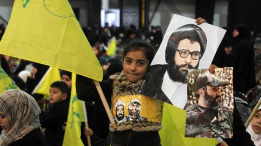 A child waves a Hezbollah flag as she holds pictures of martyrs as Hezbollah leader Sayyed Hassan Nasrallah addresses his supporters during a rally to commemorate Martyrs' Day in Beirut, February 16, 2013.  REUTERS/Sharif Karim (LEBANON - Tags: POLITICS) - RTR3DVC2
