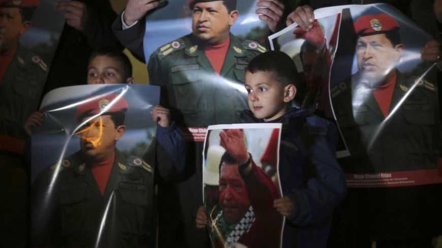 Palestinian hold posters depicting Venezuela's late president Hugo Chavez during a vigil outside the Venezuelan consulate in the West Bank city of Ramallah March 6, 2013. Chavez supported the Palestinian statehood aspirations. REUTERS/Mohamad Torokman (WEST BANK - Tags: OBITUARY POLITICS TPX IMAGES OF THE DAY) - RTR3ENOH