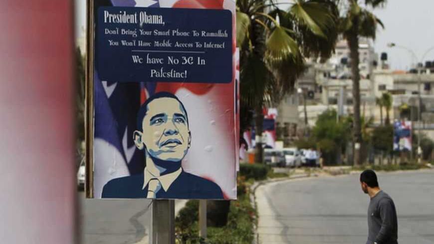 A Palestinian man walks near placards designed by an activist depicting U.S. President Barack Obama, ahead of his visit to the region, in the West Bank city of Ramallah March 12, 2013. The White House has yet to officially announce the dates for the trip, but Israeli news media have reported that Obama will arrive in the region on March 20. REUTERS/Ammar Awad (WEST BANK - Tags: POLITICS) - RTR3EVUU