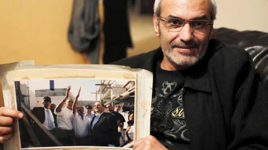 Pinhas Amar, poses for a portrait as he displays a photograph taken when he met the then-U.S. presidential candidate Barack Obama after a Palestinian rocket damaged his house, during an interview with Reuters in the southern town of Sderot March 11, 2013. If there is one thing that seems to unite Israelis and Palestinians days before Obama's visit to Israel, the occupied West Bank and Jordan next week, it is their talk of broken promises and lack of hope that he will ever bring peace. Picture taken March 11
