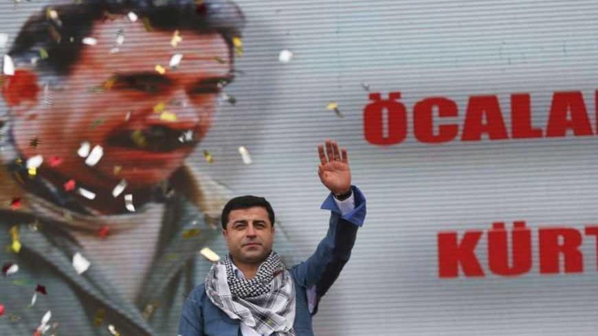 Selahattin Demirtas, co-chairman of the pro-Kurdish Peace and Democracy Party, greets his supporters during a rally to celebrate the spring festival of Newroz in Istanbul March 17, 2013. A picture of imprisoned PKK leader Abdullah Ocalan is seen in the background. REUTERS/Murad Sezer (TURKEY - Tags: POLITICS CIVIL UNREST) - RTR3F4BY