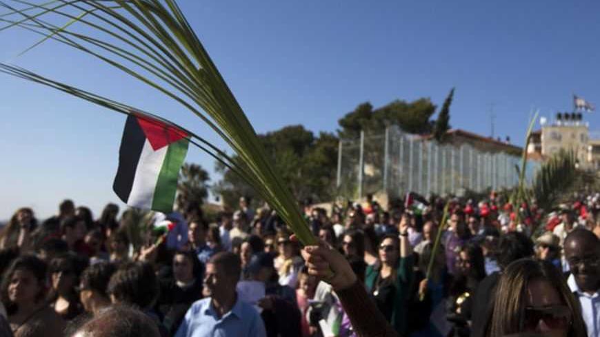 A Catholic worshipper holds a palm frond with a Palestinian flag during a Palm Sunday procession on the Mount of Olives in Jerusalem March 24, 2013. REUTERS/Ronen Zvulun (JERUSALEM - Tags: RELIGION) - RTXXVUR