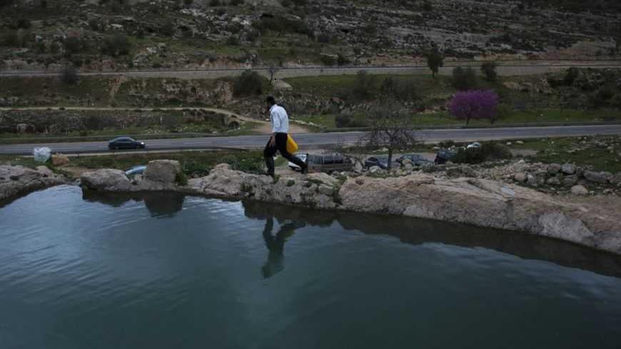An Ultra-Orthodox Jewish man walks next to a spring water reservoir before taking part in the ritual of "Mayim Shelanu" near Jerusalem March 17, 2013. The water is used to prepare matza, traditional unleavened bread eaten during the upcoming Jewish holiday of Passover. Passover commemorates the flight of Jews from ancient Egypt, as described in the Exodus chapter of the Bible. REUTERS/Ronen Zvulun (WEST BANK - Tags: RELIGION) - RTR3F4JW