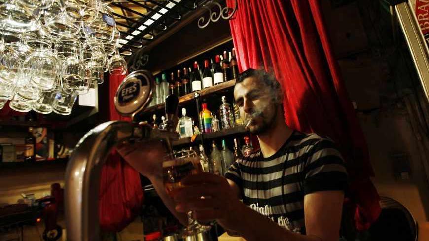 Bartender Samet Kardas smokes as he serves beer at a bar in Istanbul July 14, 2009. Smokers in Turkey tempted to flout an imminent ban in cafes, restaurants and bars will be spared execution as allegedly meted out in 17th-Century Istanbul -- but their Prime Minister has likened cigarettes to terrorism. That's a measure of how strongly Tayyip Erdogan feels about tobacco. Sultan Murad IV is said to have roamed the streets ordering the execution of those who defied a smoking ban aimed at curbing coffee house s