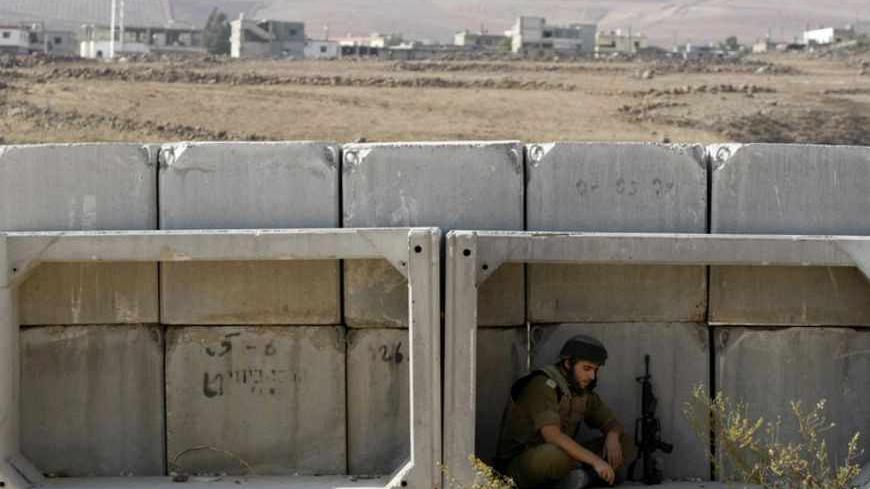 An Israeli soldier sits behind concrete blocks in the village of Ghajar on the Israeli-Lebanese border November 17, 2010. Israel said on Wednesday it would withdraw troops from the village straddling the Lebanese border, in a gesture to the United Nations that drew residents onto the streets protesting the division of their community. REUTERS/Baz Ratner (POLITICS) - RTXUQYD