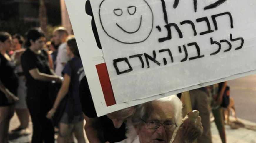 An Israeli Holocaust survivor holds a sign calling for social justice for all human beings, during a demonstration in Tel Aviv against racism and the government's policy regarding African migrants on July 28, 2012. Israel's government is planning tough new legislation against migrants, with the cabinet on July 22, approving stiff fines or six months in jail for illegal residents sending money home.  AFP PHOTO/DAVID BUIMOVITCH         (Photo credit should read DAVID BUIMOVITCH/AFP/GettyImages)