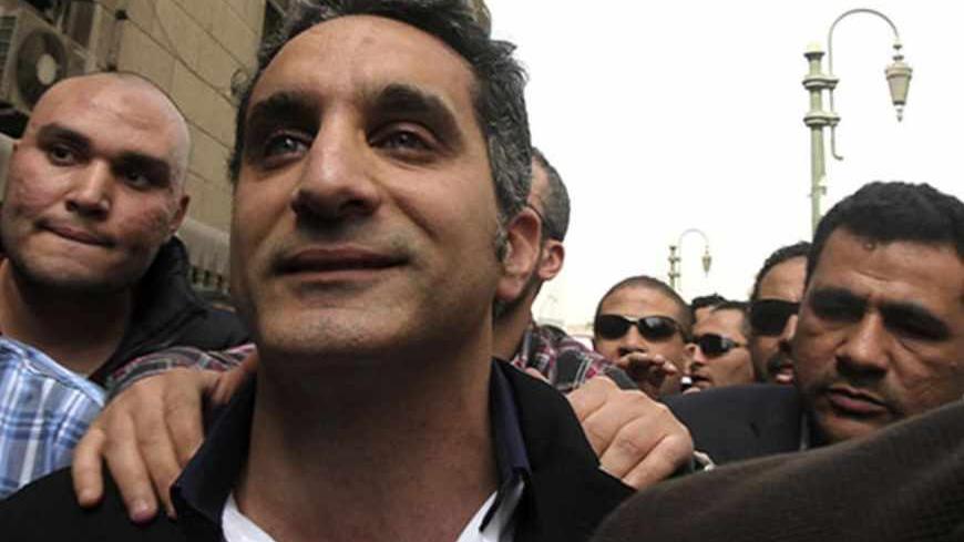 Bassem Youssef (C), the country's best-known satirist, gestures to journalists and activists as he arrives at the high court to appear at the prosecutor's office in Cairo March 31, 2013. Egypt's prosecutor-general on Saturday ordered the arrest of Youssef for making fun of Islamist President Mohamed Mursi and his Muslim Brotherhood. REUTERS/Mohamed Abd El Ghany (EGYPT - Tags: POLITICS CRIME LAW SOCIETY) - RTXY3QR