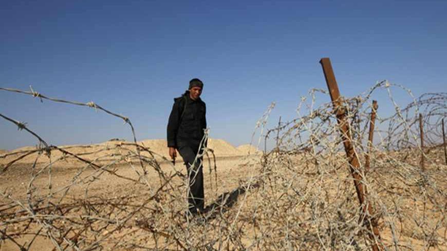 An Egyptian soldier stands behind a barbed wire fence on the border between Israel and Egypt some 50 km (30 miles) north of Eilat in this November 28, 2010 file photo, after work begun to construct a barrier to seal off part of the border with Egypt's Sinai desert. Arms smuggling by Bedouin tribal networks, mainly by land along Egypt's southern border with Sudan, across the Sinai peninsula and into the Hamas-run Gaza Strip is on the uptick, according to an Egyptian official, who asked not to be named. Sudan