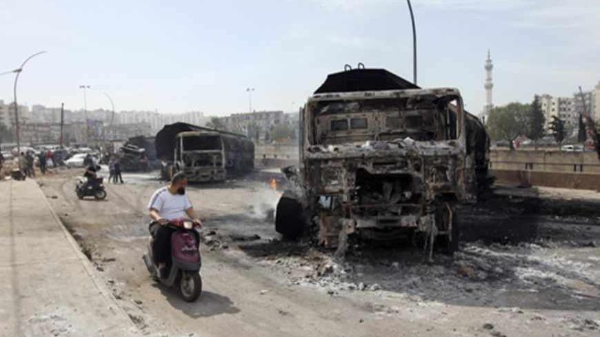 A man rides his motorcycle near damaged fuel tanker trucks in Tripoli, northern Lebanon March 15, 2013. Seven Syria-bound fuel tanker trucks were burned and destroyed in Tripoli on Friday, according to the National News Agency. REUTERS/Omar Ibrahim (LEBANON - Tags: POLITICS CIVIL UNREST ENERGY) - RTR3F10L
