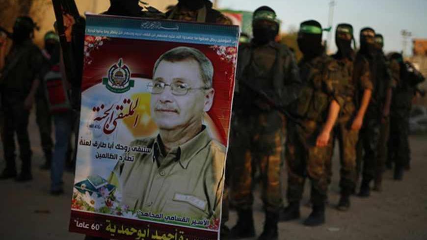 A Hamas militant holds a poster of Maysara Abu Hamdeya before a protest in the northern Gaza Strip April 2, 2013. Israeli prison guards fired tear gas to quell disturbances by Palestinian inmates on Tuesday after a prisoner serving a life sentence over an attempt to bomb an Israeli cafe died of cancer. Maysara Abu Hamdeya's death threatened to raise tensions in the Israeli-occupied West Bank, where Palestinians, who view jailed brethren as heroes in a fight for statehood, have held several protests in recen