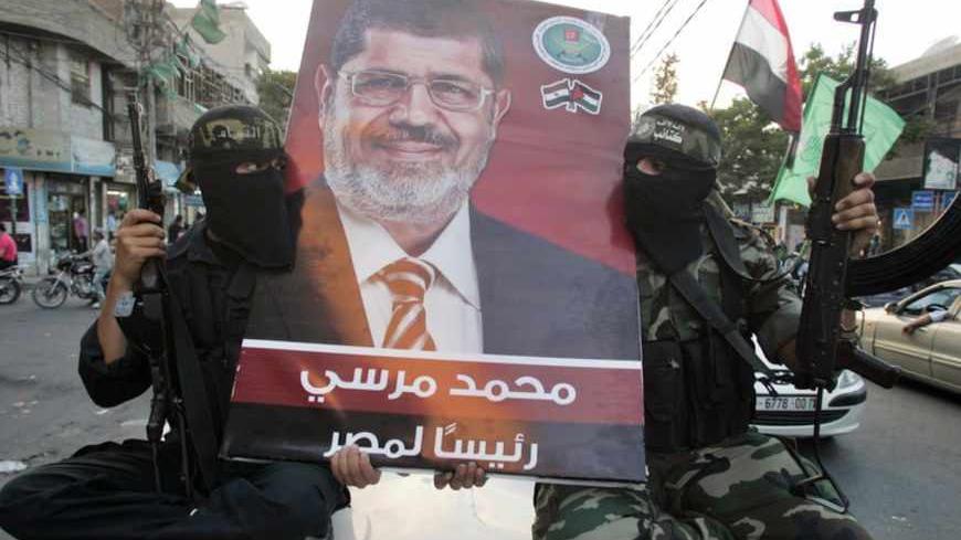 Hamas militants hold a poster depicting Mohamed Morsy of the Muslim Brotherhood as they celebrate in the street in Gaza City after he was declared Egypt's first democratic president June 24, 2012. Morsy's win was hailed by Hamas, the Islamist group governing Gaza and which is locked in a power-struggle with the West Bank-based, U.S.-backed Palestinian Authority of President Mahmoud Abbas. REUTERS/Mohammed Salem (GAZA - Tags: POLITICS ELECTIONS TPX IMAGES OF THE DAY MILITARY) - RTR343IV
