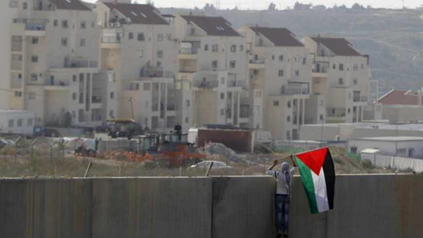 A Palestinian protester places a flag on the controversial Israeli barrier during clashes with Israeli security officers (unseen) after a rally marking the 48th anniversary of the founding of the Fatah movement, in the West Bank village of Bilin near Ramallah, January 4, 2013. REUTERS/Ammar Awad (WEST BANK - Tags: POLITICS CIVIL UNREST TPX IMAGES OF THE DAY) - RTR3C3OA
