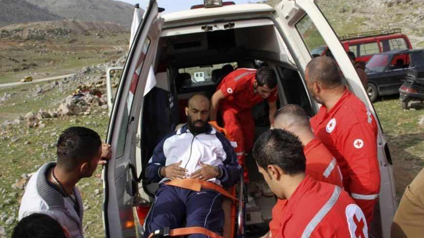 Lebanese Red Cross personnel move a Syrian refugee, who fled the fighting in his country, into an ambulance in the Shebaa region, March 21, 2013. Witnesses said at least 150 Syrians had fled the fighting and crossed the border into Lebanon's Shebaa region, just north of the Golan. Many of them crossed on foot or by donkey through rugged snow-capped terrain around Mount Hermon. REUTERS/Karamallah Daher (LEBANON - Tags: POLITICS CIVIL UNREST) - RTR3FAGK
